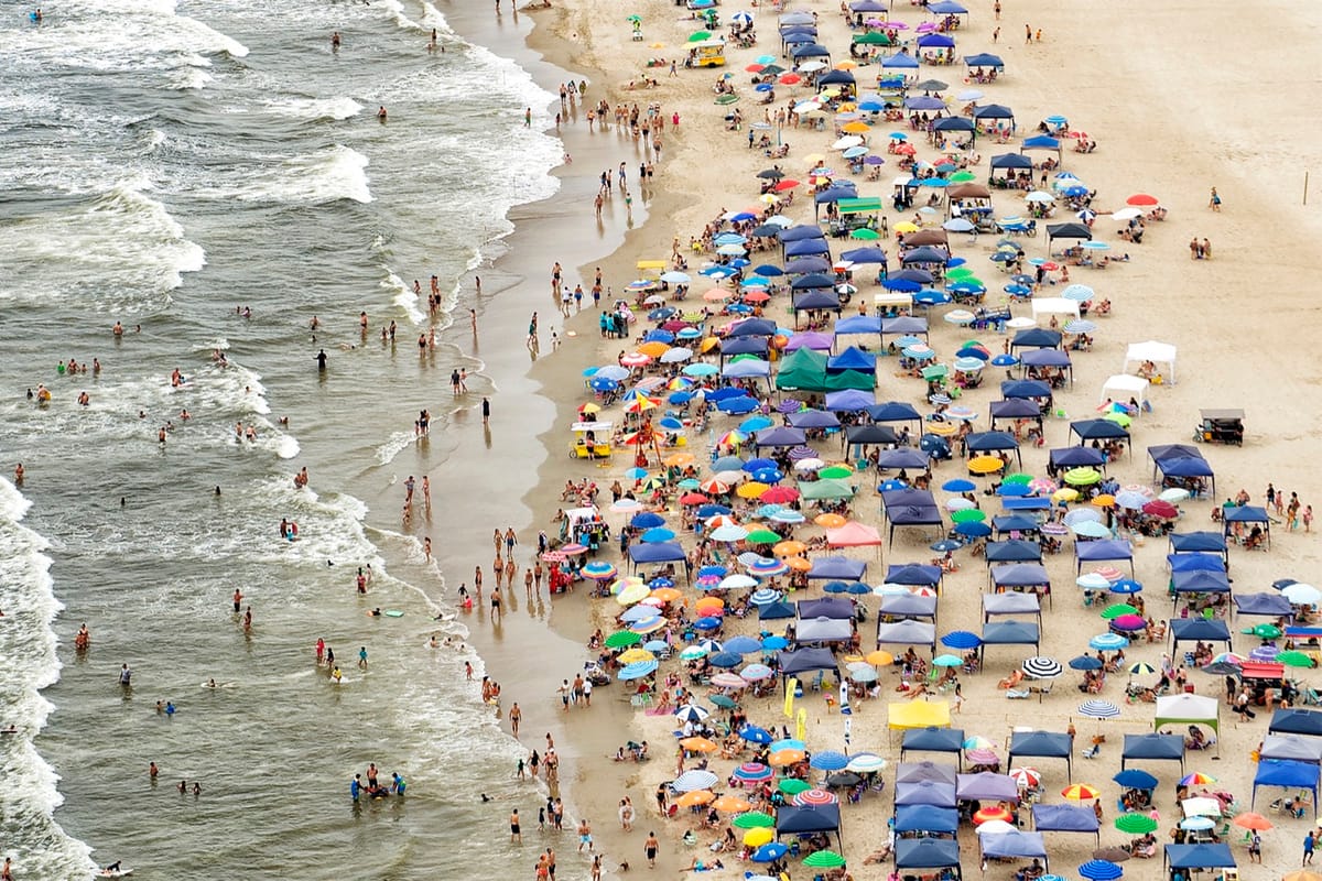 Vista aérea de praia cheia de guarda-sóis coloridos à beira do mar