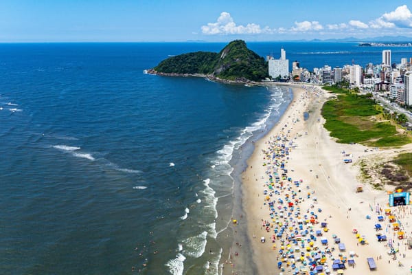 Vista aérea da Praia de Caiobá lotada de guarda-sóis, com o Morro do Boi ao fundo